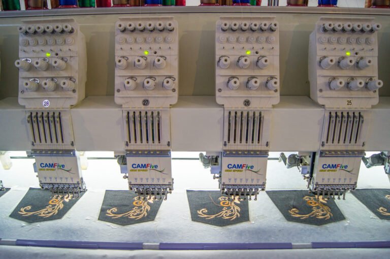 Bordadora plana CAMFive con 4 cabezales bordando el mismo diseño al mismo tiempo sobre tela.