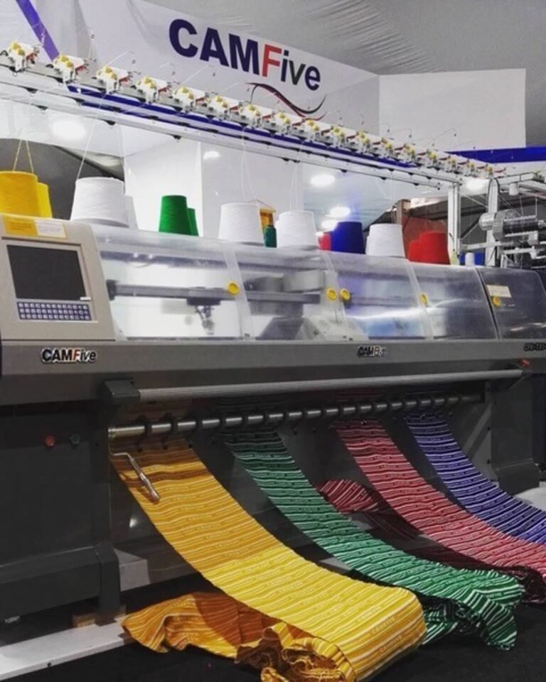Tejedora industrial CAMFive de 3 sistemas en operación, tejiendo cuellos con alto detalle y eficiencia.